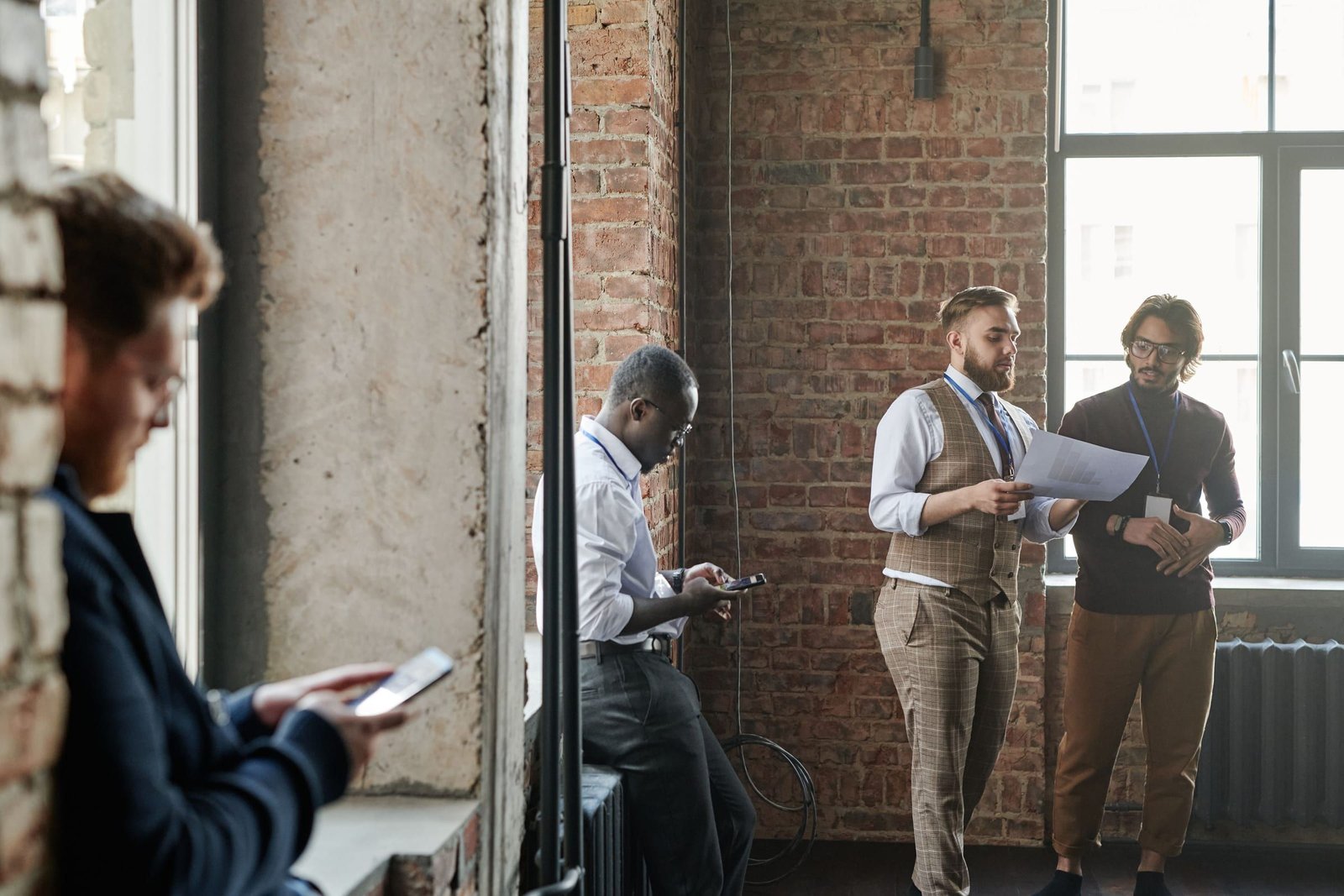 Jeunes professionnels en tenue business casual qui échangent debout dans un loft en briques.